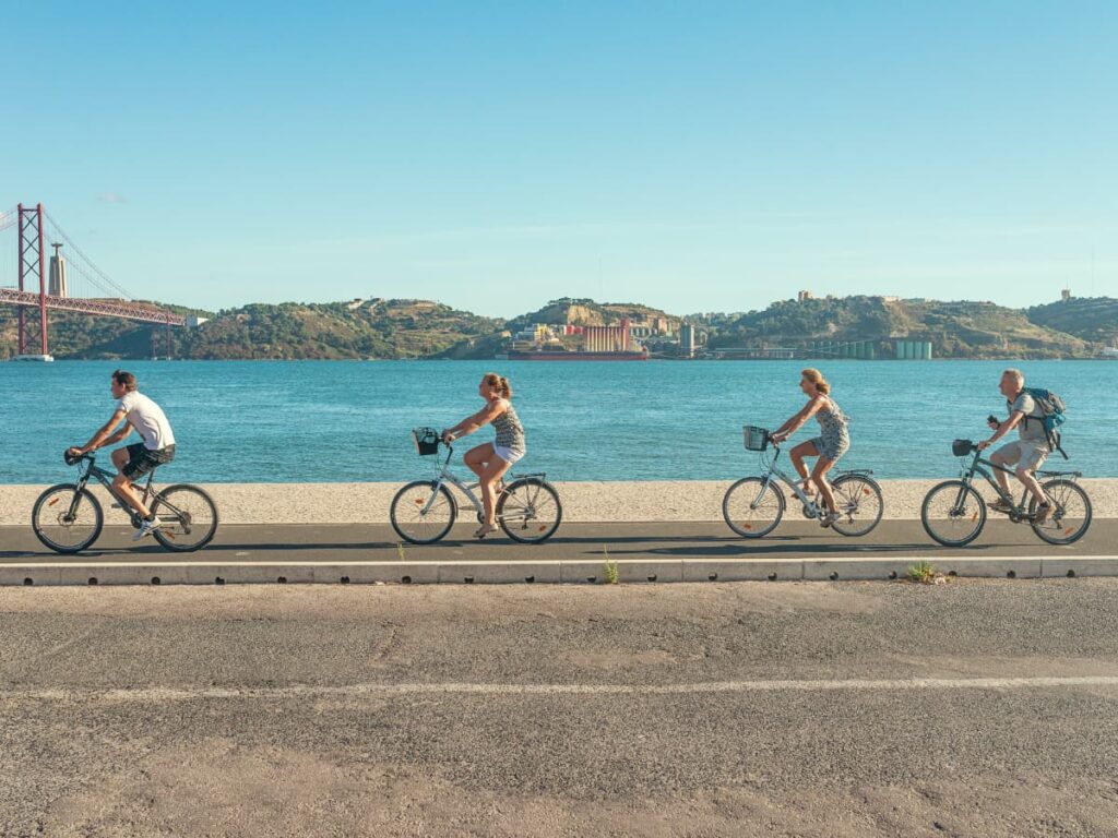 Four people biking along the Tagus River, in Lisbon, Portugal.