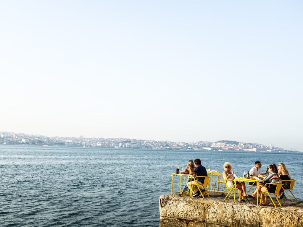 A group of people having a meal in the Ponto Final Restaurant overlooking the Tagus River, in Lisbon, Portugal.